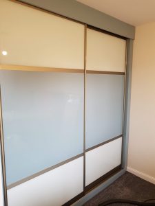 Sliding wardrobe with centre panel of blue sparkle glass and pure white top and bottom panels. Complemented by a champagne frame.